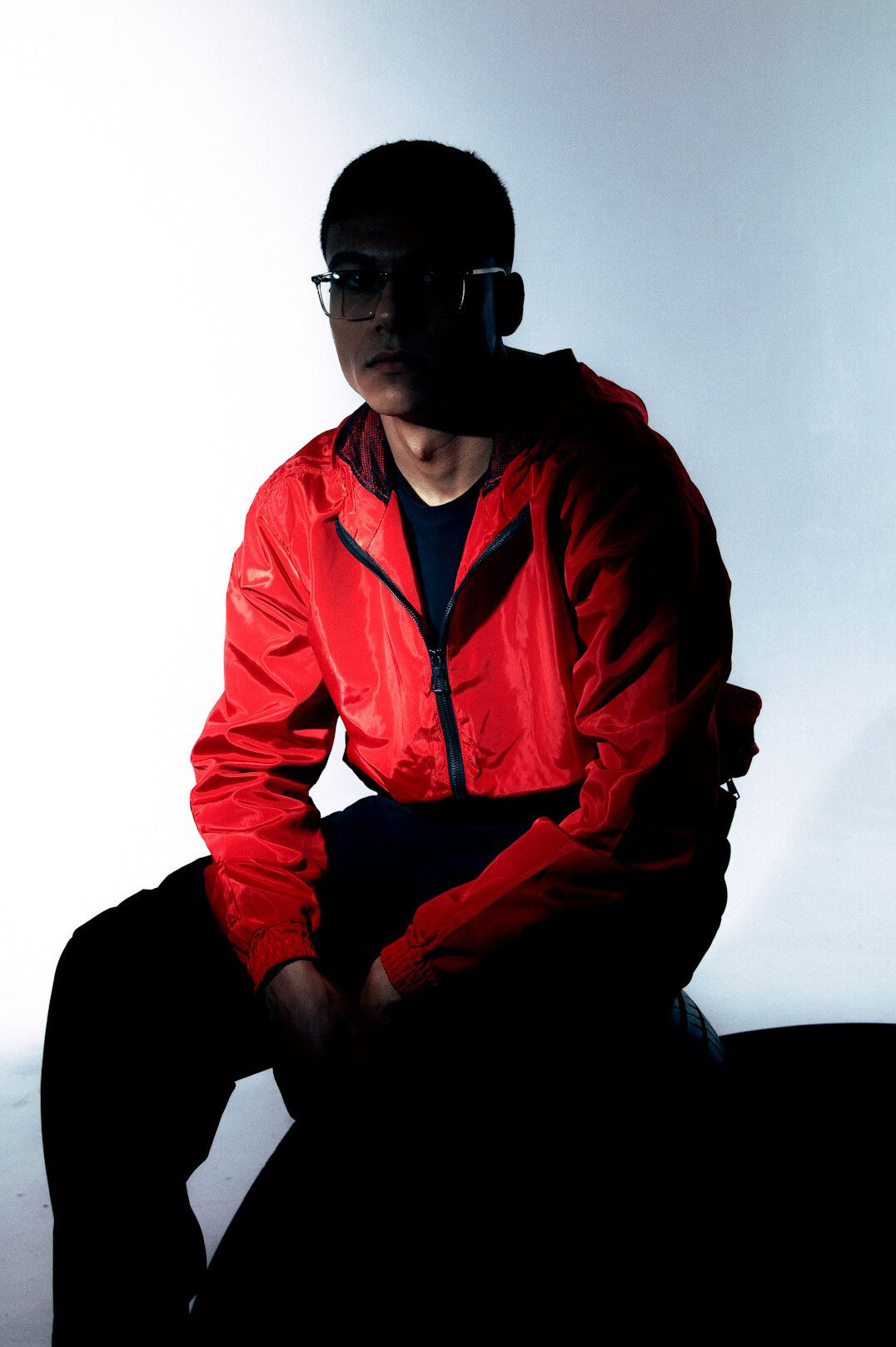 Man with short black hair and glasses wearing a casual jacket in a tech studio